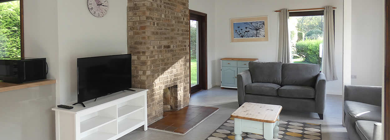 Light and spacious lounge with comfortable sofas and TV in one of our standard cottages